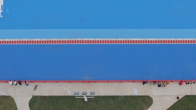 Top Down Drone Shot of People on Blue Athletics Track