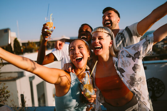 Diverse friends laughing and celebrating on summer rooftop party