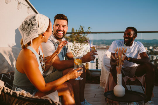 Happy diverse friends enjoying drinks and conversation on a summer rooftop