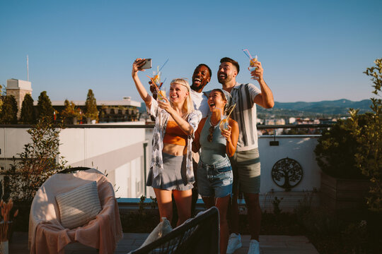 Excited friends capturing rooftop party selfie