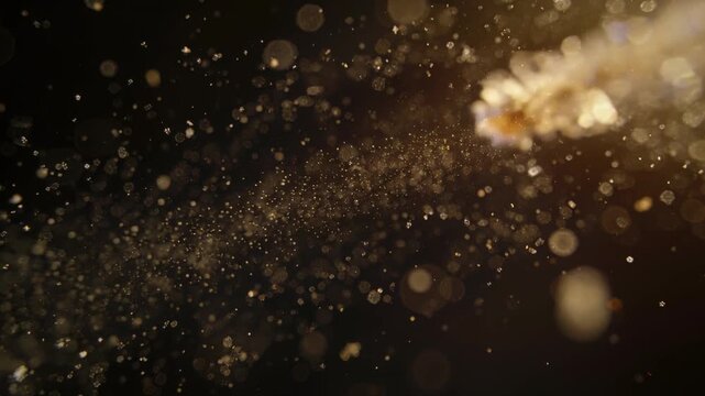 Shifting camera angle revealing facets, thin filament shedding crystals and dust in studio bokeh