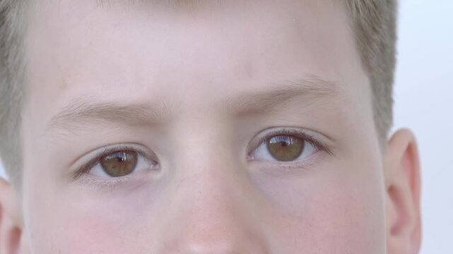 close-up part child's face, boy 10 years old Asian-European appearance, human eyes looking seriously at camera, violence on young lives, emotional scars