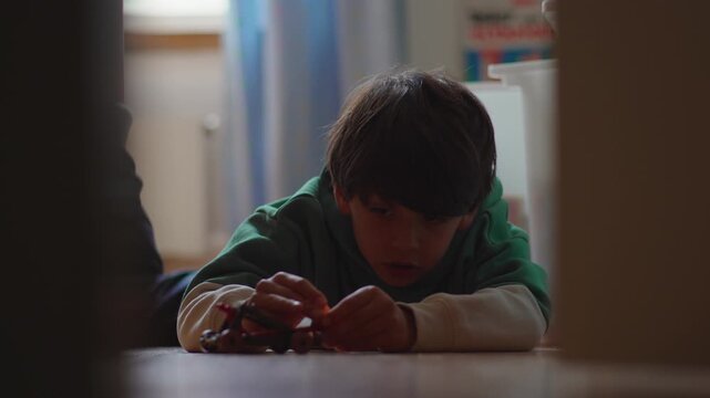 Young boy aiming and launching toy catapult while playing on bedroom floor at home, highlighting concentration, imaginative play, childhood learning and creativity