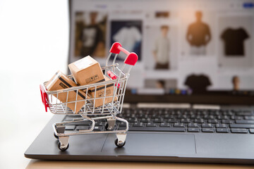 Mini shopping cart with small cardboard boxes on laptop keyboard. Online shopping and e-commerce concept. © Rangsarit