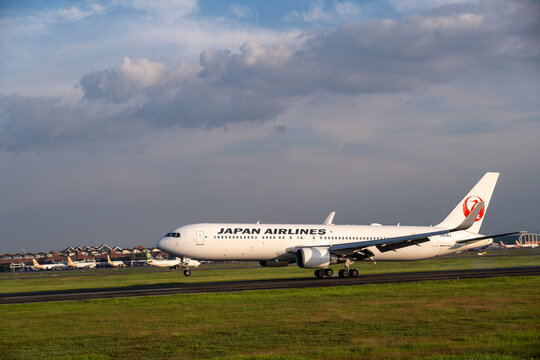 Jakarta, Indonesia - May 28, 2026: A Japan Airlines Boeing 767 aircraft touching down on the runway at Soekarno-Hatta International Airport under a cloudy blue sky.