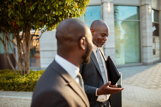 Two business professionals talking while walking outside an office building