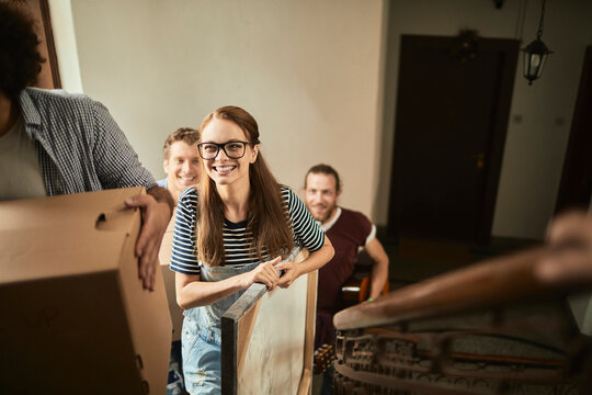 Young friends moving boxes up apartment stairs