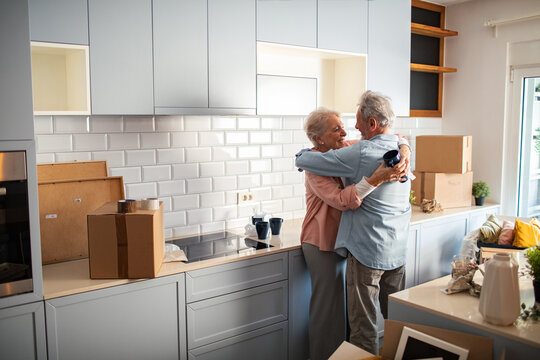 Senior couple hugging in modern kitchen after moving home