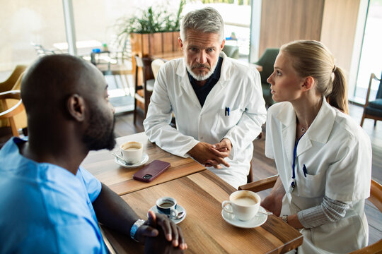 Doctors and nurses discuss over coffee in hospital cafeteria