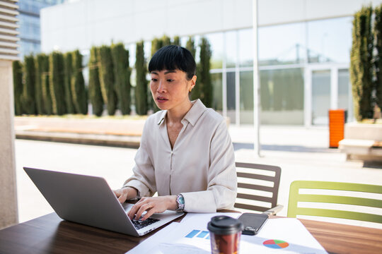 Businesswoman working on laptop outdoors at office courtyard