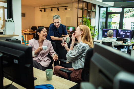 Coworkers sharing coffee and laughter in modern creative office