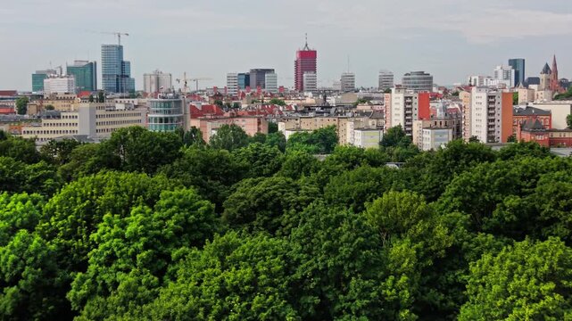 City Skyline Green Urban Park Forest Treetops Architecture Real Estate Development Aerial View. Panoramic drone perspective showcases dense green park trees seamlessly Poznan
