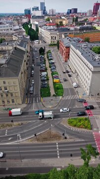 Urban Traffic Intersection Avenue Street Parking Real Estate Architecture Cityscape Skyline Aerial. This vertical high-angle drone view captures a busy metropolitan avenue with a central green median 