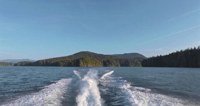 Vessel leaving wake on calm water past coastline