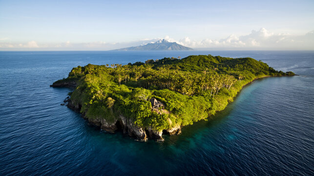 Aerial view of lush green island surrounded by clear blue ocean and distant mountain range in the background