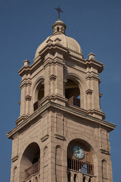 Tacna Cathedral presides over the main plaza in warm rose-tinted stone under an immaculate deep blue sky, its twin baroque bell towers and ornate neoclassical facade creating one of the most architect