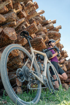 Gravel cyclist resting by wood logs exploring outdoors