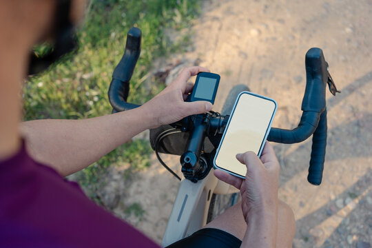 Cyclist checking smartphone and cycling computer navigation on gravel route