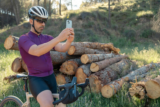 Male cyclist capturing nature scene with smartphone