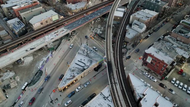 Aerial view of urban city intersection with elevated train tracks and construction zone at sunset.