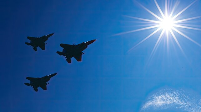 Three jets fly in formation against a bright sunlit blue sky