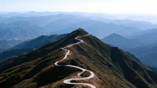 Winding road ascends rugged, misty mountain ridge to a distant summit