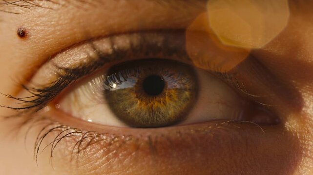 Blinking woman responding to light shift, reopening eye at closeup, showing cornea reflection, mole