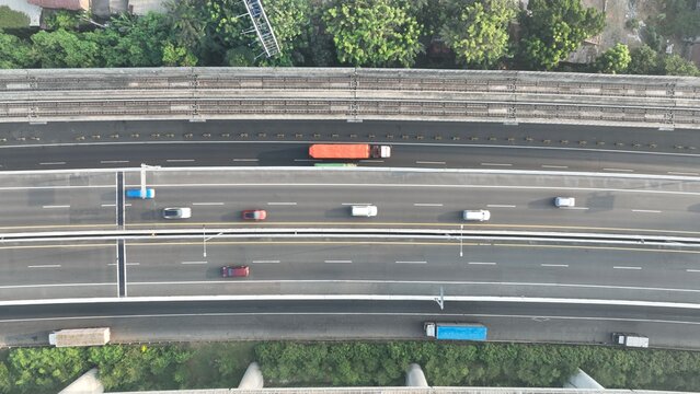 Aerial view of a multi-lane highway with cars and trucks driving along the asphalt road in Bekasi Barat, West Java, Indonesia.