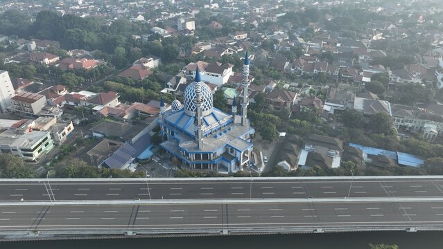 Aerial view of the Al-Azhar Mosque with its distinctive blue dome and minarets situated near a highway in a residential area of Bekasi Barat, West Java, Indonesia.