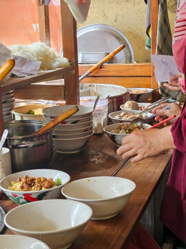 The baso trader is preparing orders for customers looking bowls in a row, the theme of Indonesian traditional food, meatball stalls, service, culinary 