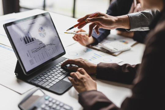 Business team analyzing financial data on laptop screen.