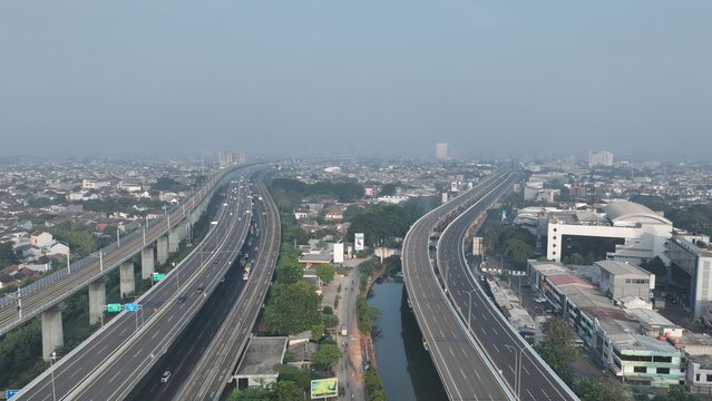 Aerial view of the elevated highway and railway tracks winding through the dense urban landscape of Bekasi Barat, West Java, Indonesia.