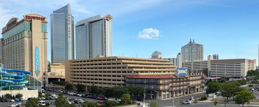 Panoramic view of Atlantic City casino hotels and urban skyline featuring Showboat and Hard Rock resorts, multi-level parking garage, waterpark slides, and summer tourism under a clear sky