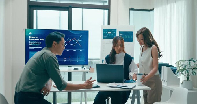 Group of Asian businesspeople work together discuss plan idea with investment data profit sale statistics in business meeting in office. Financial generation z team brainstorm on e-Commerce project.