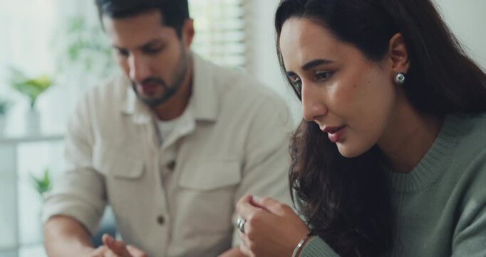 Unhappy young Latin man and woman discussing finance debt and bankruptcy on the couch at home. Marriage divorce difficulty, serious relationship separation problem, couple counseling therapy concept.