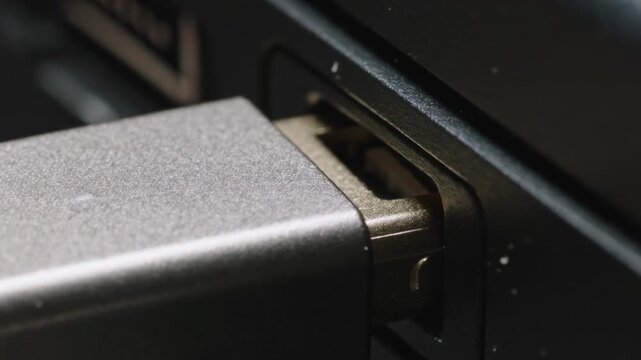 Positioning adult hand aligning USB connector, inserting into laptop side port, connecting device