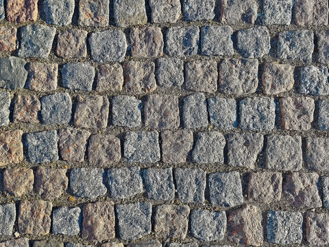 Texture of stone pavement showing rough surface with irregular shapes and colors found in urban areas