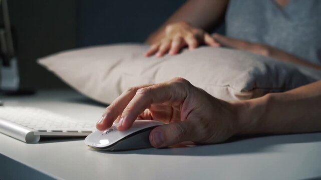 Reaching partner smoothing pillow as right hand clicking white mouse at home desk for comfort