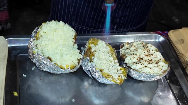 Melting Cheese on Stuffed Baked Potatoes with Blowtorch at Street Food Stall