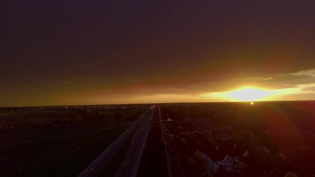 Golden sunset over suburban city skyline with clouds and glowing orange sky. Evening with sun rays breaking through storm clouds