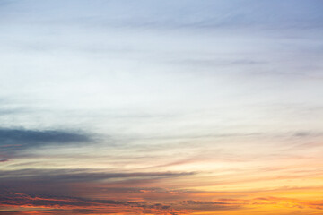 Fototapeta premium Colorful sunset sky with soft clouds and warm orange, pink and blue tones. Natural background ideal for travel, nature, weather and design projects.