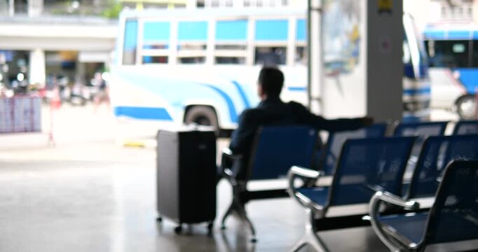 Blurry passenger with suitcase waiting at bus station terminal