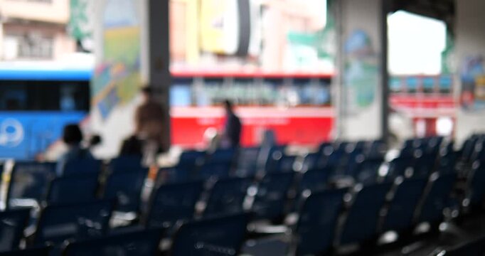 Rows of blue chairs in bus terminal with blurry buses background
