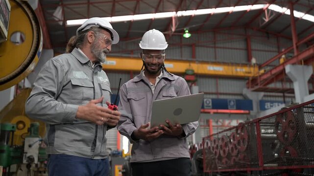 Factory engineers using laptop computer on manufacturing floor