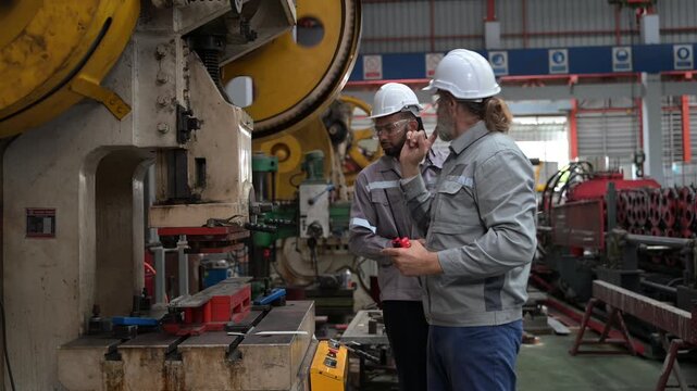 Engineers using walkie talkie near heavy press machine