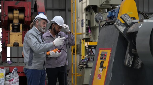 Two diverse engineers operating heavy industrial press machine