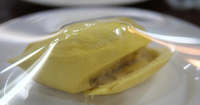 Close up of yellow durian pulp wrapped in plastic wrap on plate
