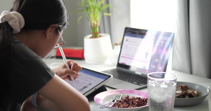 Rear view of young Asian woman thinking and working at desk