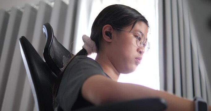 Side view of young Asian woman focused working on computer