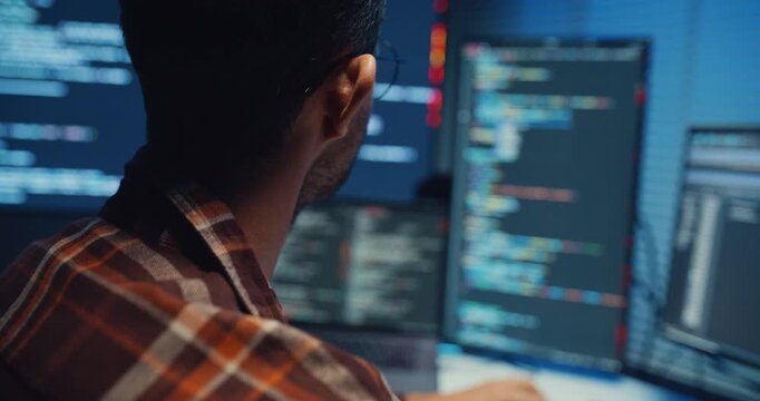 Close up young Male programmer hands typing on keyboard in dark home office at night. AI technology, cybersecurity, software developer, freelance innovation, database system, digital network concept.